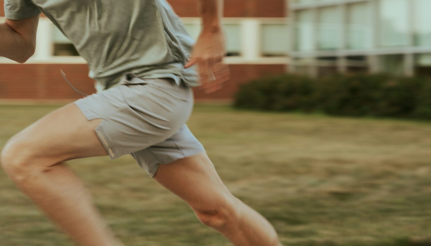 a man in shorts and a t - shirt is playing with a frisbee