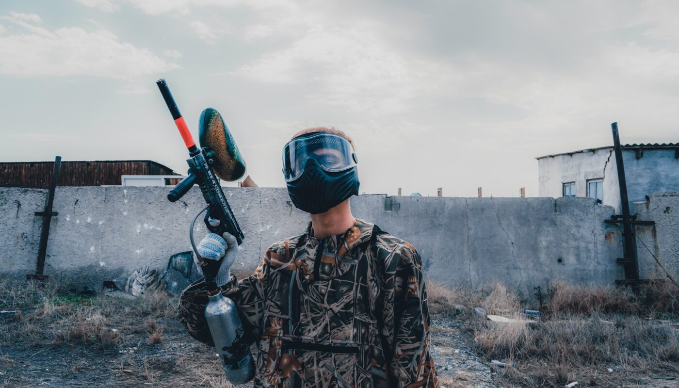 man wearing mask holding paintball gun during daytime